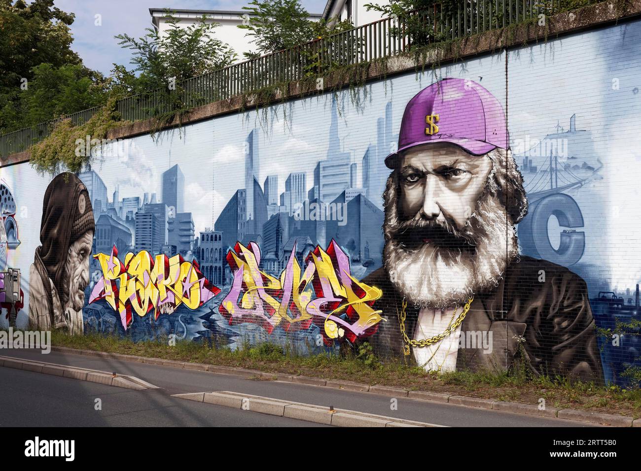 Karl Marx como hombre capitalista y sin hogar en yuxtaposición, retratos frente al horizonte de la gran ciudad, mural socialmente crítico por los artistas callejeros Foto de stock