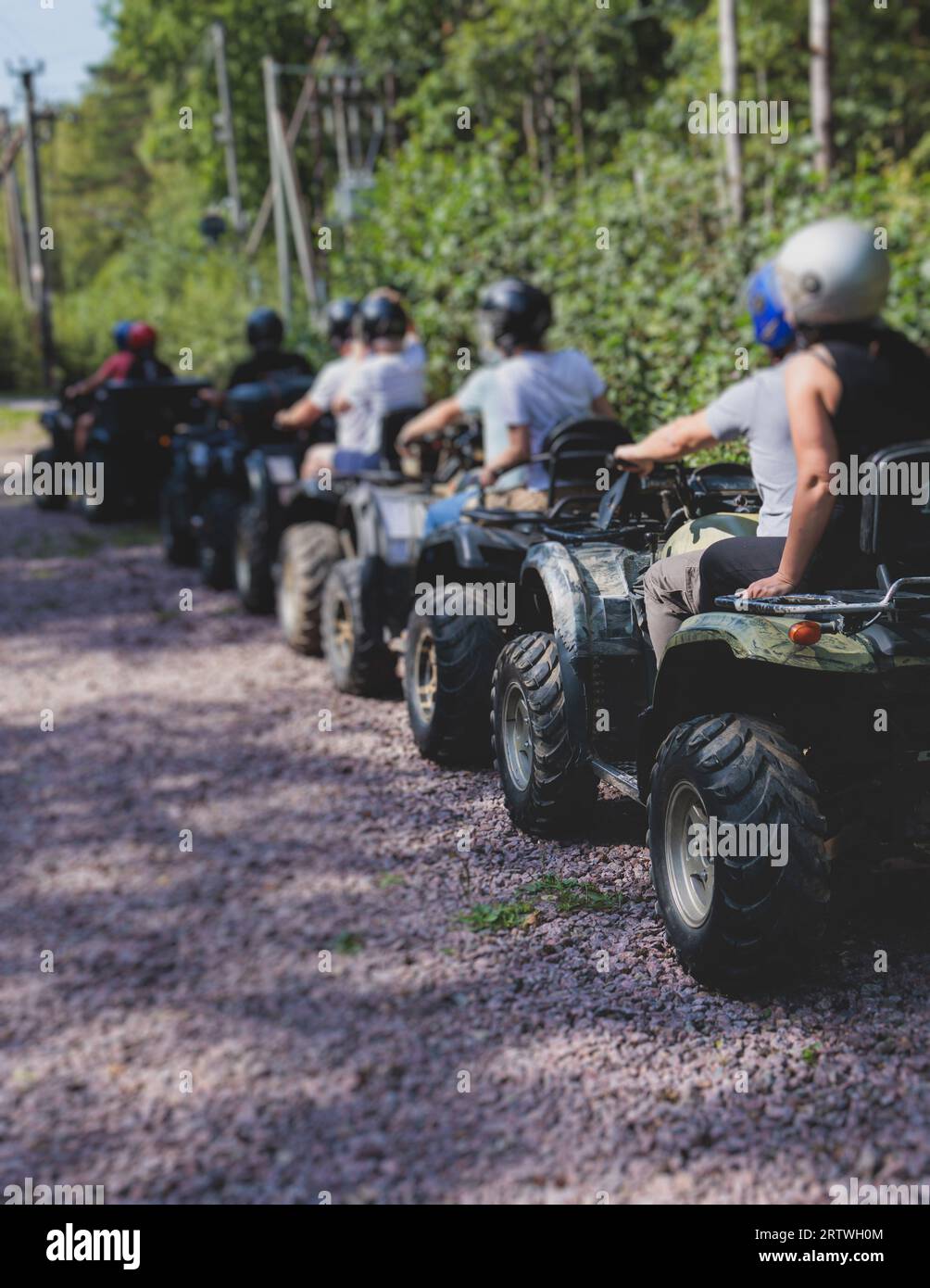 Grupo de jinetes que montan vehículo de ATV que cruzan la carretera rural del bosque, proceso de conducir un vehículo de alquiler, todo terreno vehículo de la bici quad, durante tou tou fuera de la carretera Foto de stock
