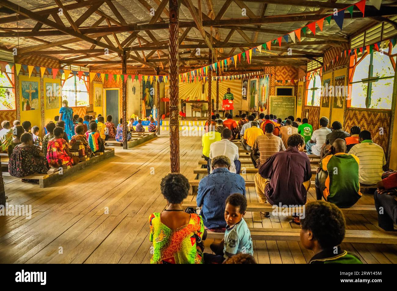 Palembe, Papúa Nueva Guinea, julio de 2015: Foto de personas nativas sentadas en bancos de madera durante la misa en la iglesia de madera en Palembe, río Sepik en Papúa Foto de stock