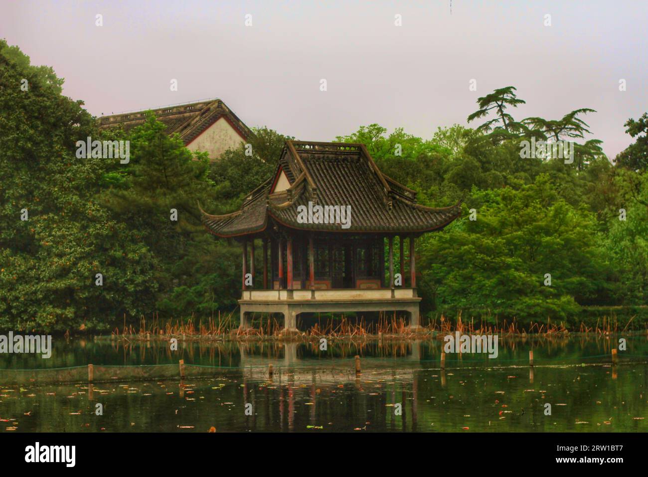 Capture el encanto sereno de un río que serpentea a través de las casas tradicionales y la exquisita belleza de la naturaleza en el abrazo de China. Foto de stock