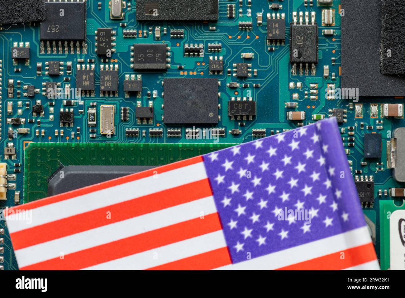 Un concepto de tecnología estadounidense con una bandera estadounidense en la parte superior de una placa de circuito semiconductor. Foto de stock