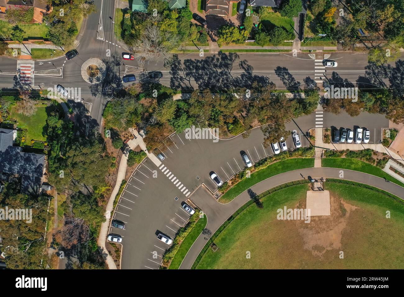 Vista aérea, drone de la intersección de la rotonda y aparcamiento curvo cerca de un parque para perros en Sydney, Australia Foto de stock