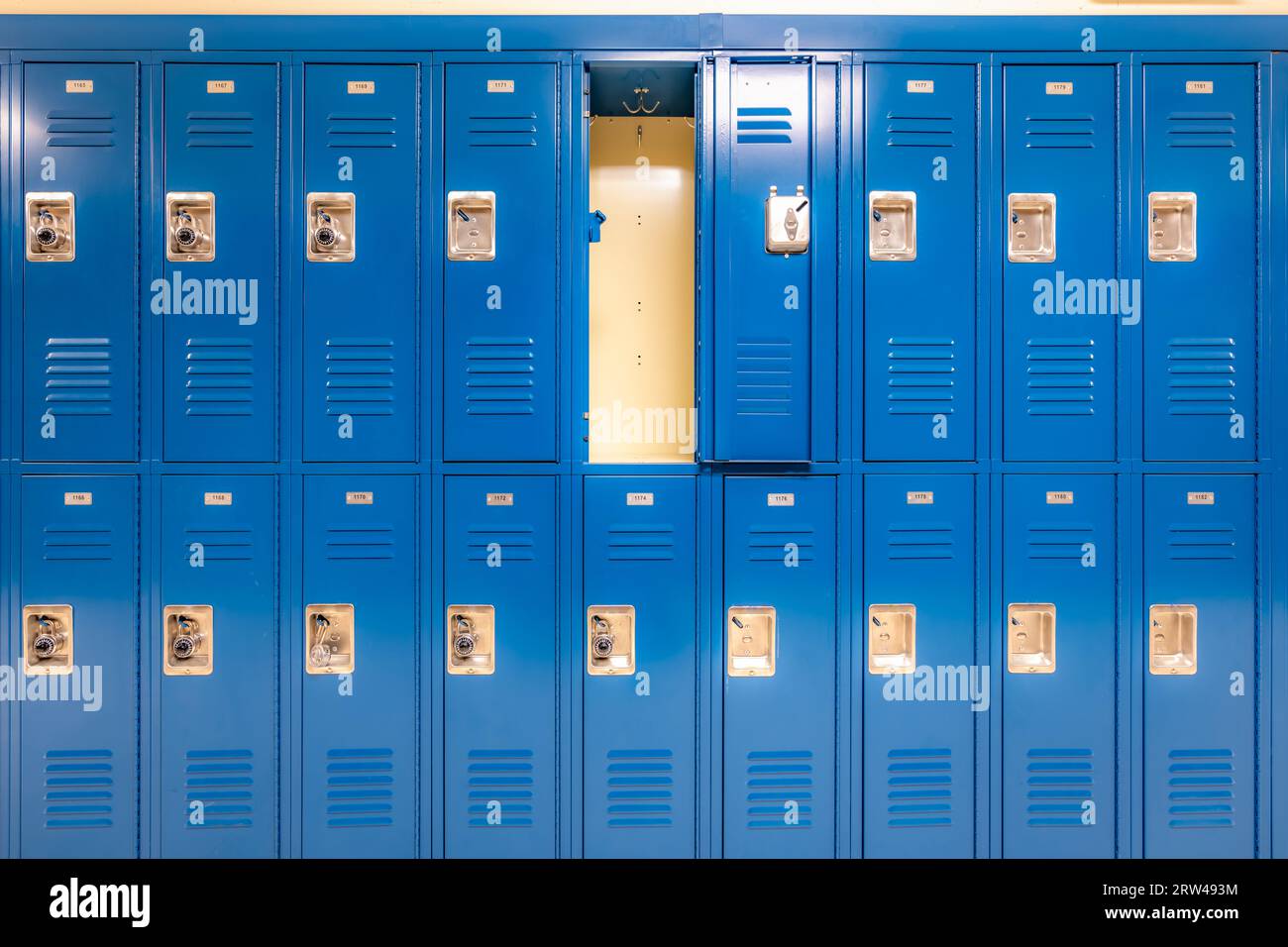 Una sola taquilla de metal azul vacía abierta a lo largo de un pasillo indescriptible en una escuela secundaria típica de EE.UU. Foto de stock