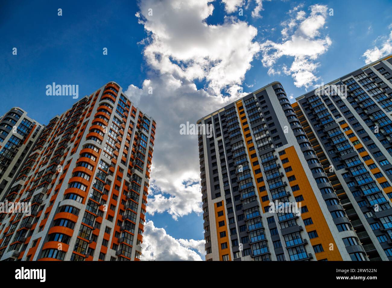 edificios de apartamentos de gran altura recién construidos sobre fondo de cielo azul con nubes blancas. Foto de stock