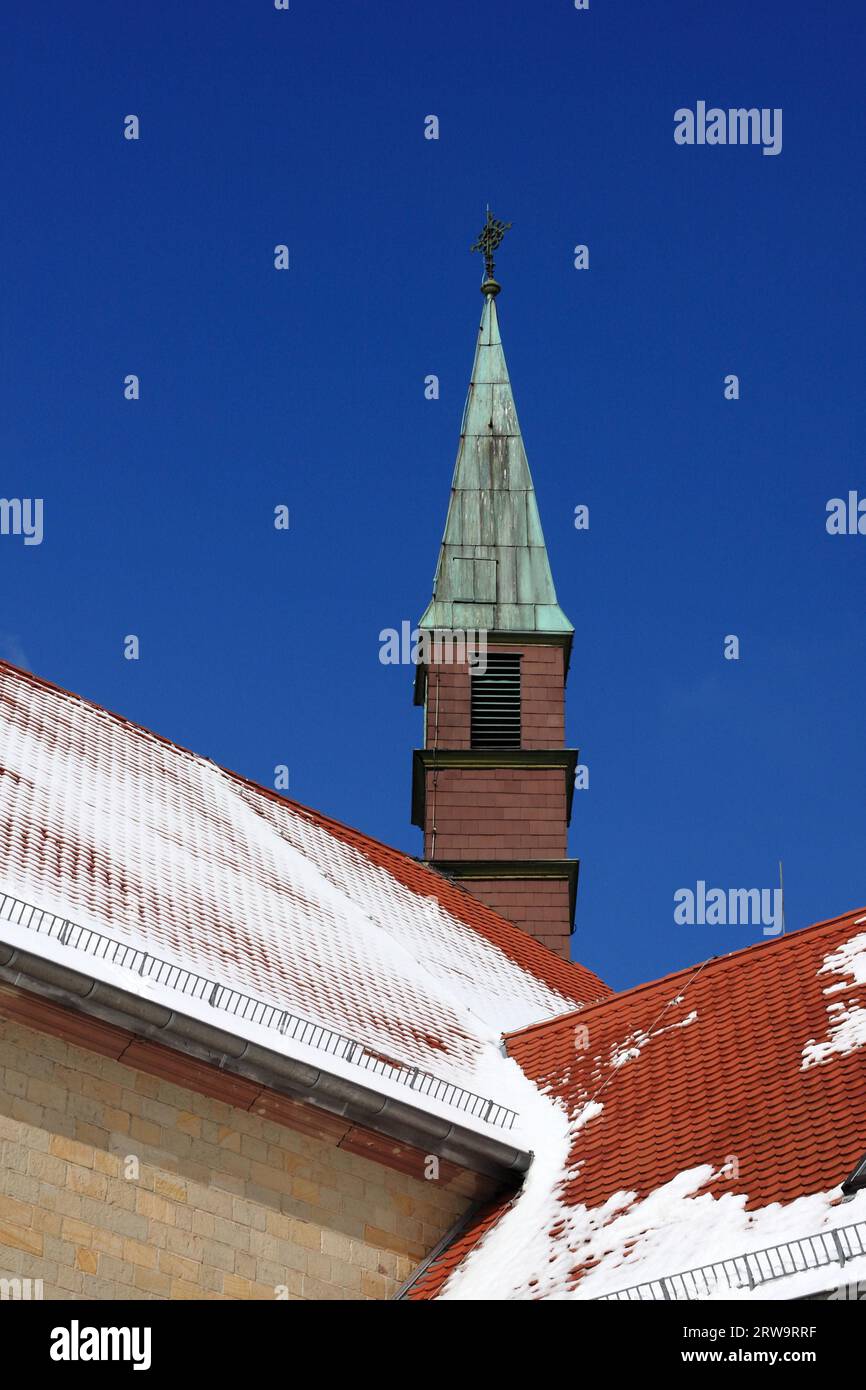 Torre del antiguo monasterio en St. Ingbert, techos cubiertos de nieve en primer plano, fondo cielo azul Foto de stock