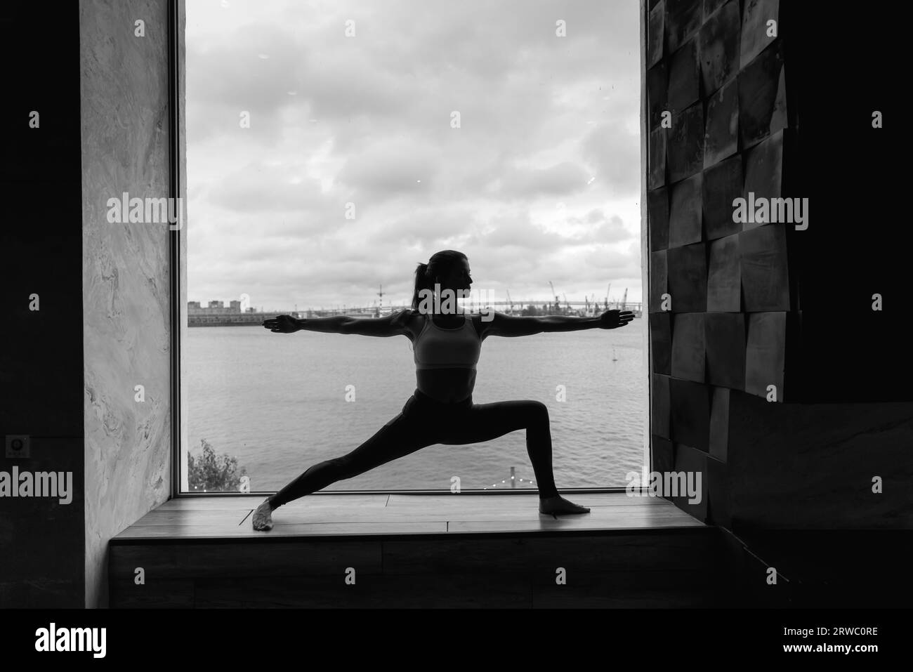 Silueta de mujer joven haciendo yoga en pose de héroe. Concepto de entrenamientos en casa de cuarentena. Espacio publicitario. Foto de alta calidad Foto de stock