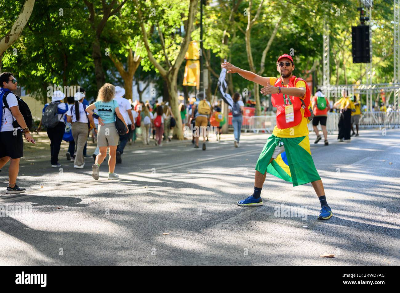 Un voluntario brasileño dirigiendo a los rebaños de peregrinos en su camino a la Santa Misa de apertura en el primer día de las Jornadas Mundiales de la Juventud en Lisboa, Portugal. Foto de stock