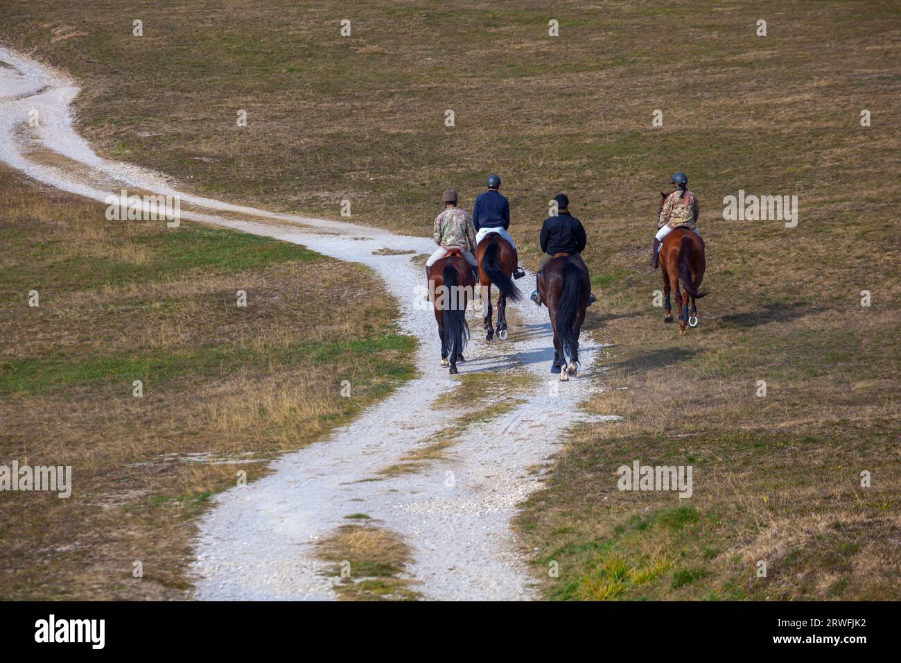 Los jinetes exploran con gracia los bastiones de Palmanova, mezclando la aventura ecuestre con la cautivadora belleza de los alrededores Foto de stock