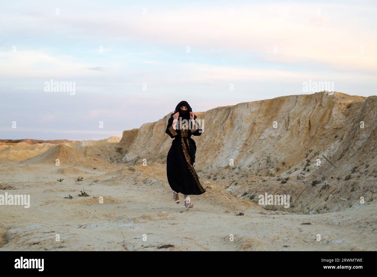 Islam mujer negro ropa nacional corre a través del desierto de danger.Woman perdió lo salvaje Foto de stock