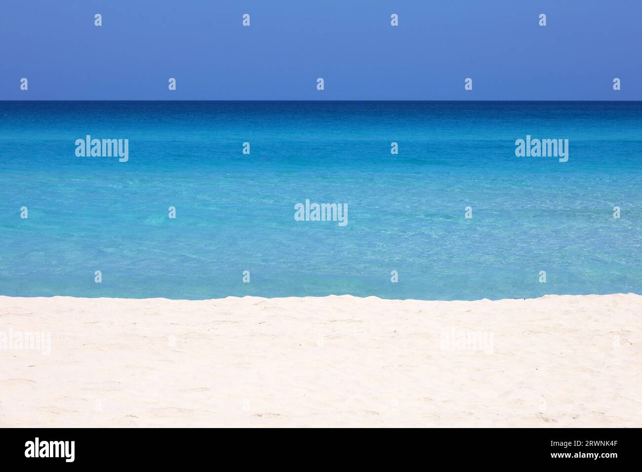 Playa de mar vacía con arena blanca, vista a las olas azules y el cielo azul. Costa caribeña, fondo para vacaciones en una naturaleza paradisíaca Foto de stock