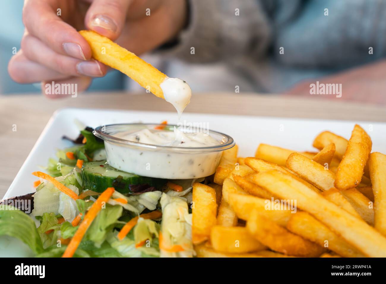Mano de la mujer sumergiendo deliciosas papas fritas en salsa de mayonesa,  salsa de queso Fotografía de stock - Alamy