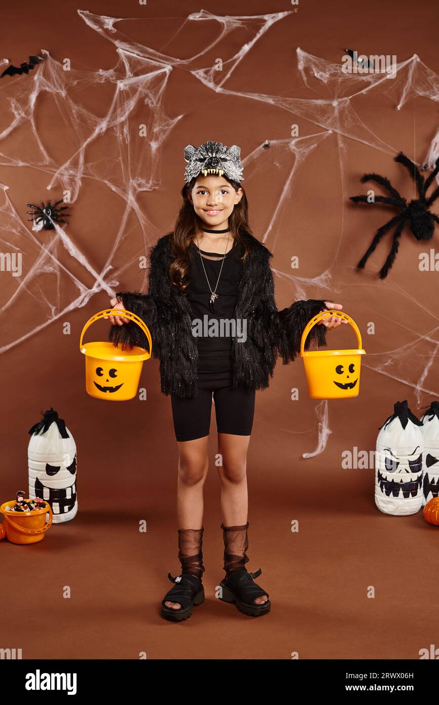 Chica feliz con dos cubos de calabaza con linternas, telaraña y arañas, concepto de Halloween Foto de stock