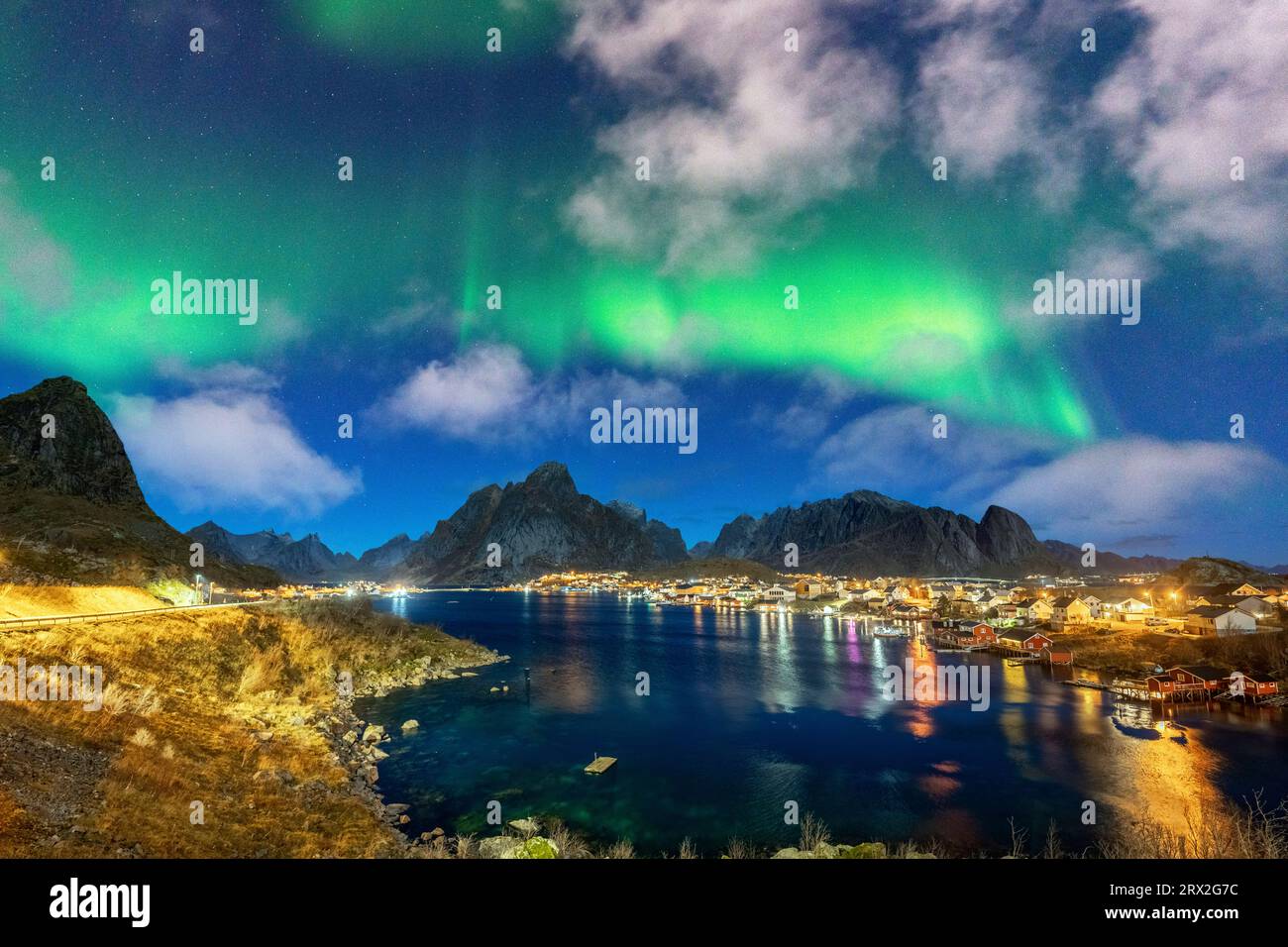 Puerto iluminado de Reine bajo las luces verdes brillantes de la Aurora Boreal (aurora boreal), Islas Lofoten, Nordland, Noruega, Escandinavia Foto de stock