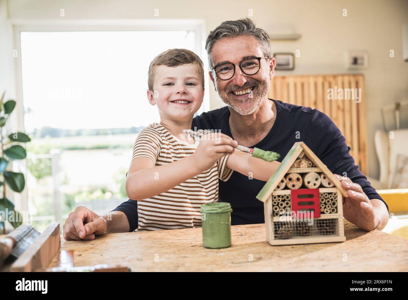 Nieto feliz pintando casa modelo por abuelo en casa Foto de stock