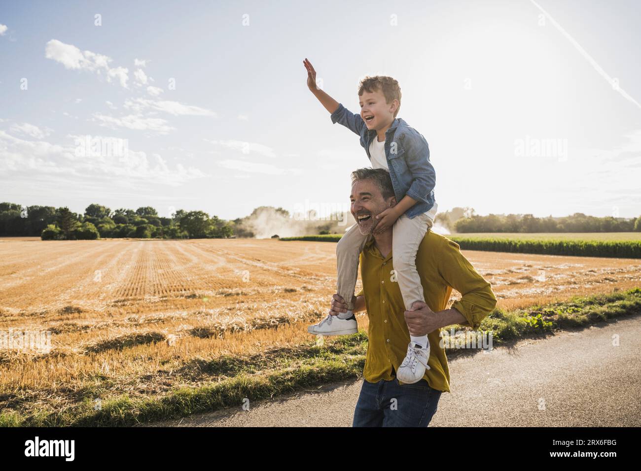 Hombre disfrutando llevando nieto en hombros en día soleado Foto de stock