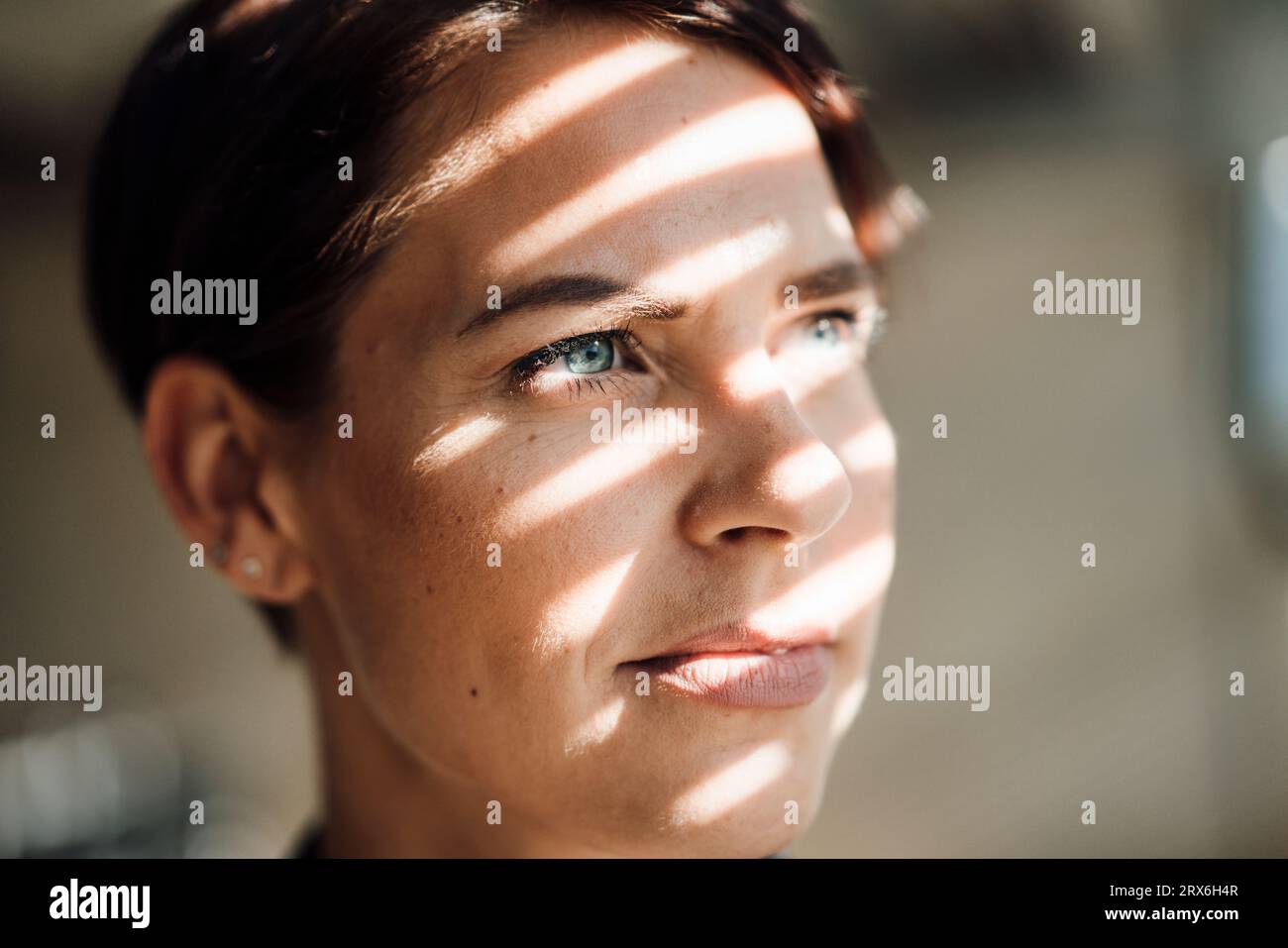 Empresaria reflexiva con la luz del sol en la cara Foto de stock