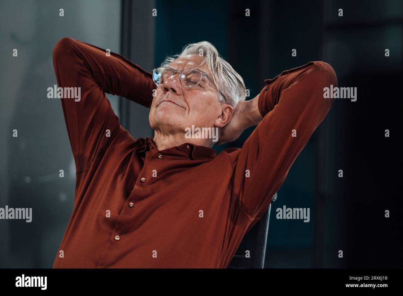 Hombre de negocios mayor con las manos detrás de la cabeza durmiendo en la oficina Foto de stock