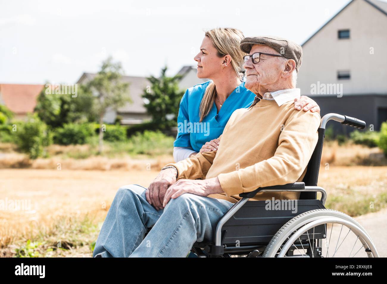 Enfermera reflexiva por el hombre mayor sentado en silla de ruedas Foto de stock