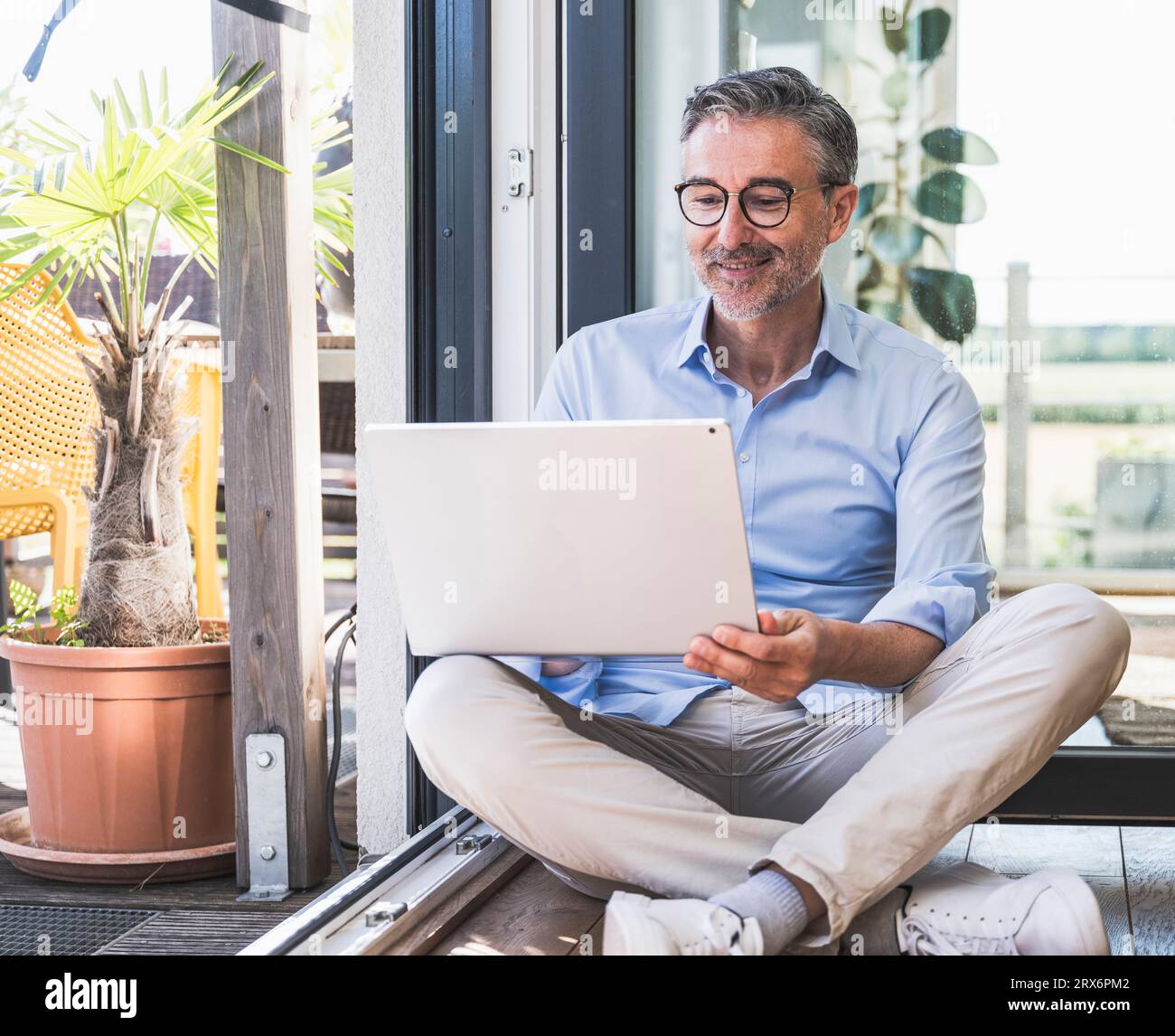 Hombre de negocios usando el ordenador portátil sentado en el piso en la oficina en casa Foto de stock