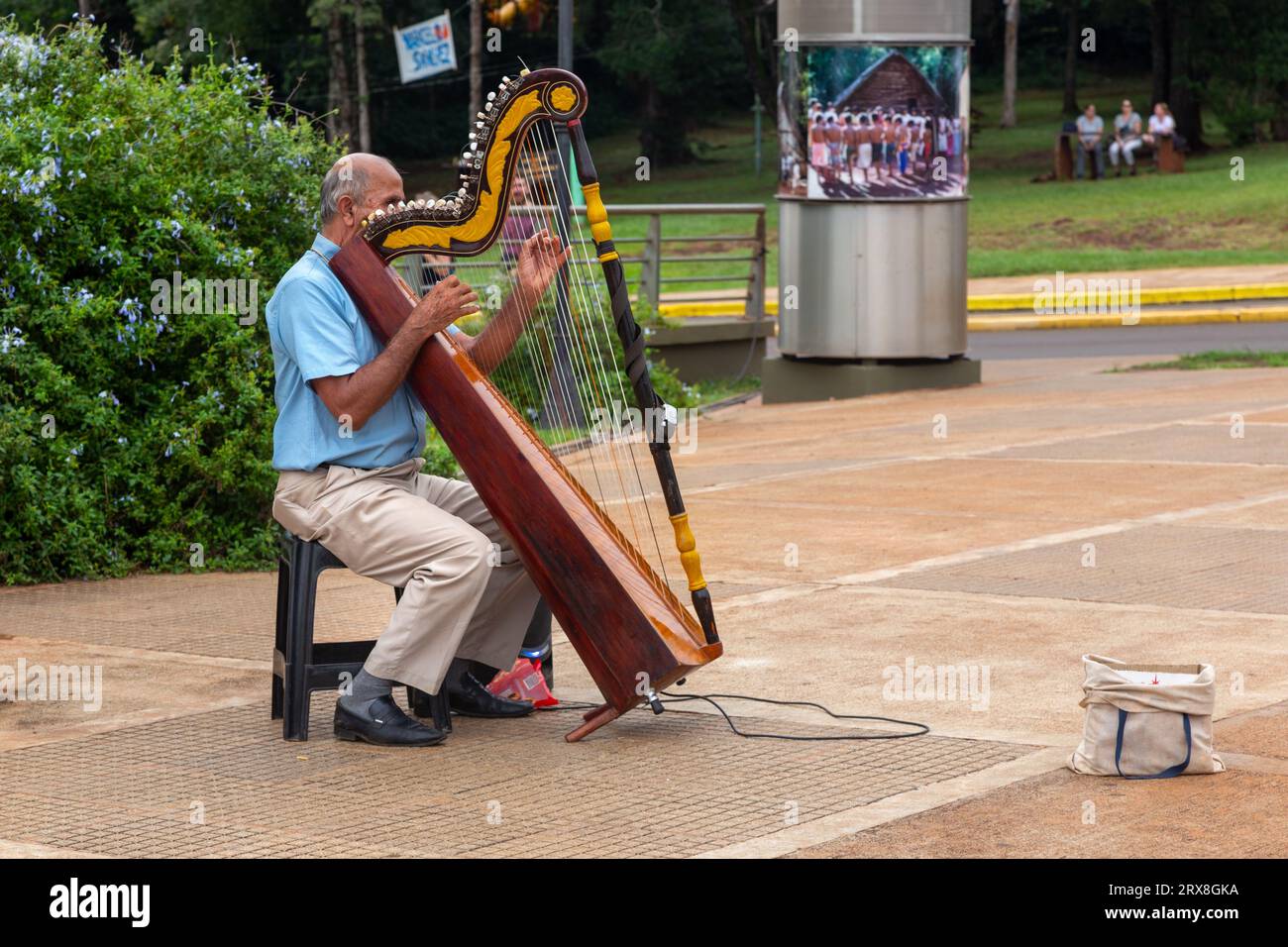 Hombre anciano sentado y tocando instrumento musical de arpa, Hito Tres Fronteras o Triple Frontera, zona Tri-Frontera entre Brasil, Argentina, Paraguay Foto de stock