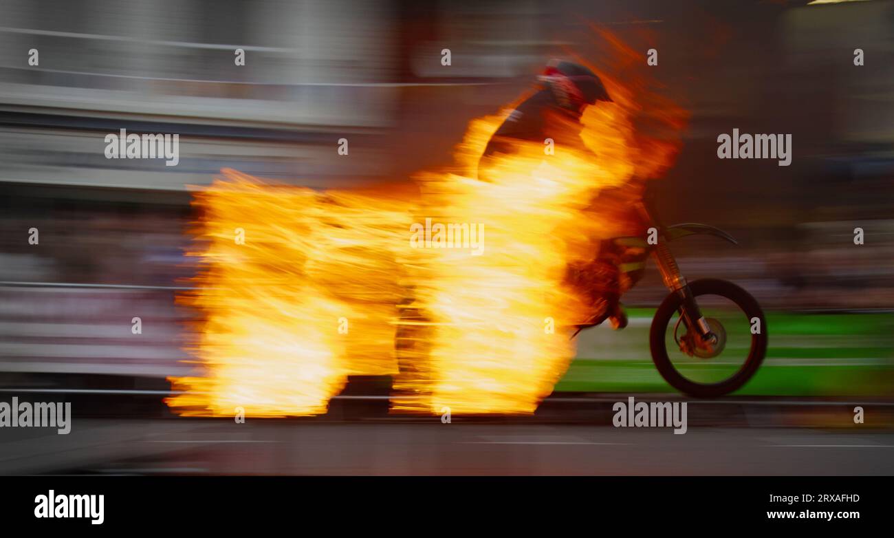 Movimiento desenfoque que muestra la velocidad de Un miembro del equipo de exhibición de la motocicleta de los niños de los cohetes saltando en Una motocicleta a través de las llamas, carnaval de Ringwood, anillo Foto de stock