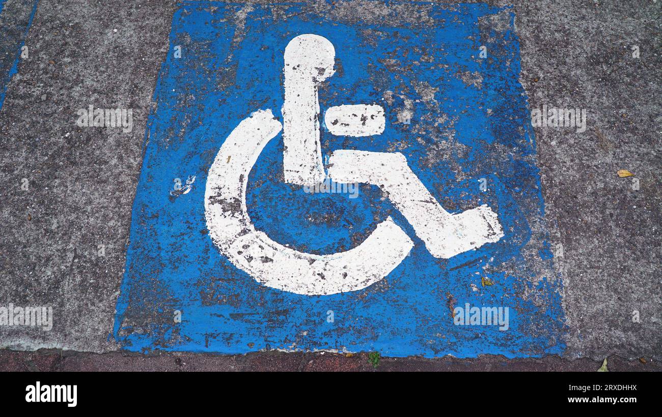 accesibilidad zona de aparcamiento para discapacitados para usuarios de sillas de ruedas con diseño de símbolo de accesibilidad marcado en azul Foto de stock