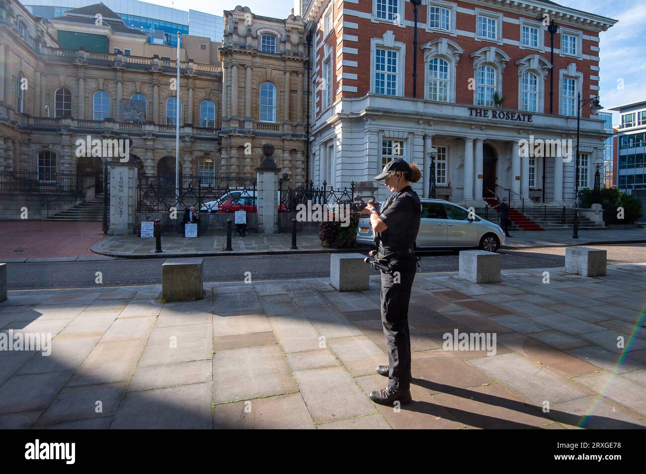 Reading, Berkshire, Reino Unido. 25º de septiembre de 2023. Un oficial de policía filma a manifestantes pacíficos sentados frente a la Corte de la Corona de Reading. Esta mañana, un grupo de seis residentes locales levantó carteles frente a la Corte de la Corona de Reading en Berkshire como parte de la campaña Defend Our Juries. En marzo de 2023, Trudi Warner, de 68 años de edad, levantó un cartel frente a la corte de la corona del interior de Londres, donde se estaba llevando a cabo un juicio climático, con las palabras “Jurados, tienes el derecho absoluto de absolver a un acusado según tu conciencia”. Crédito: Maureen McLean/Alamy Live News Foto de stock