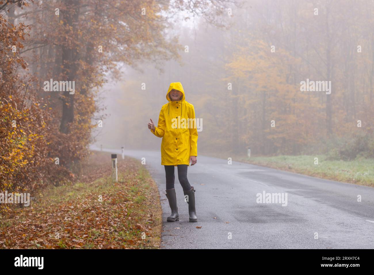 Mujer joven con chubasquero amarillo y botas de goma en la naturaleza  primaveral Fotografía de stock - Alamy