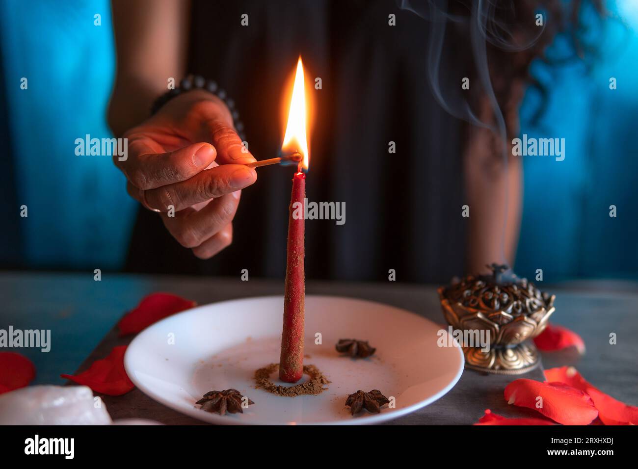 Encendiendo una vela roja, bruja en la víspera de todos los santos realizando un ritual, Halloween, creencias espirituales, magia blanca Foto de stock