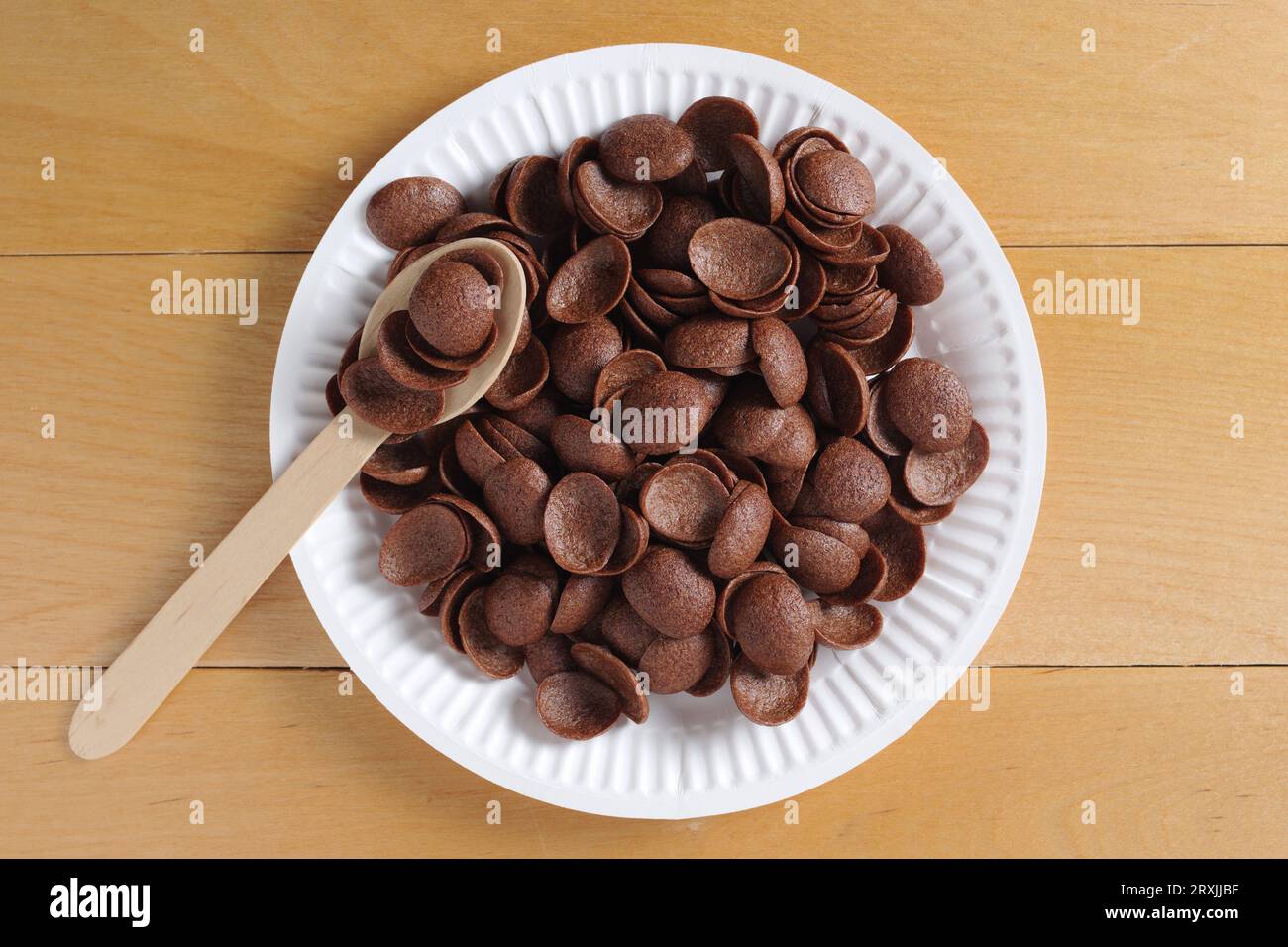 Directamente encima de la vista del desayuno de cereales de chocolate en plato desechable de cartón sobre mesa de madera Foto de stock