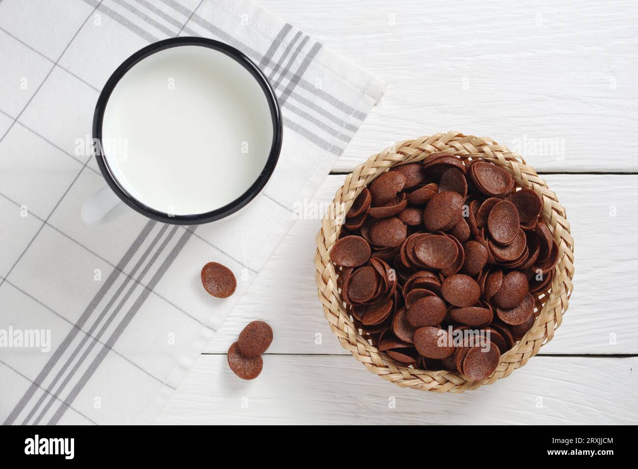 Taza de esmalte de leche y chocolate copos de maíz en la mesa de madera blanca, vista superior Foto de stock