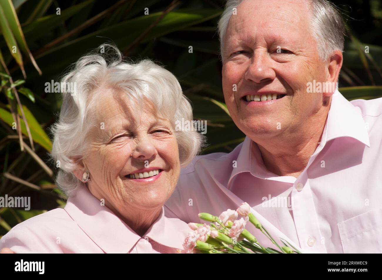 Feliz pareja mayor casada posando delante de la cámara - John Gollop Foto de stock