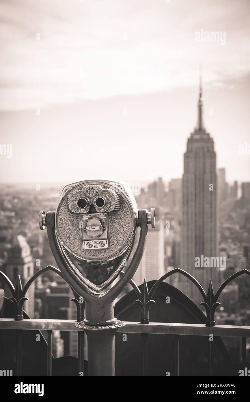 Prismáticos a la antigua usanza que funcionan con monedas con vistas al Empire State Building y el distrito circundante en Midtown Manhattan desde Top of the Rock In Foto de stock