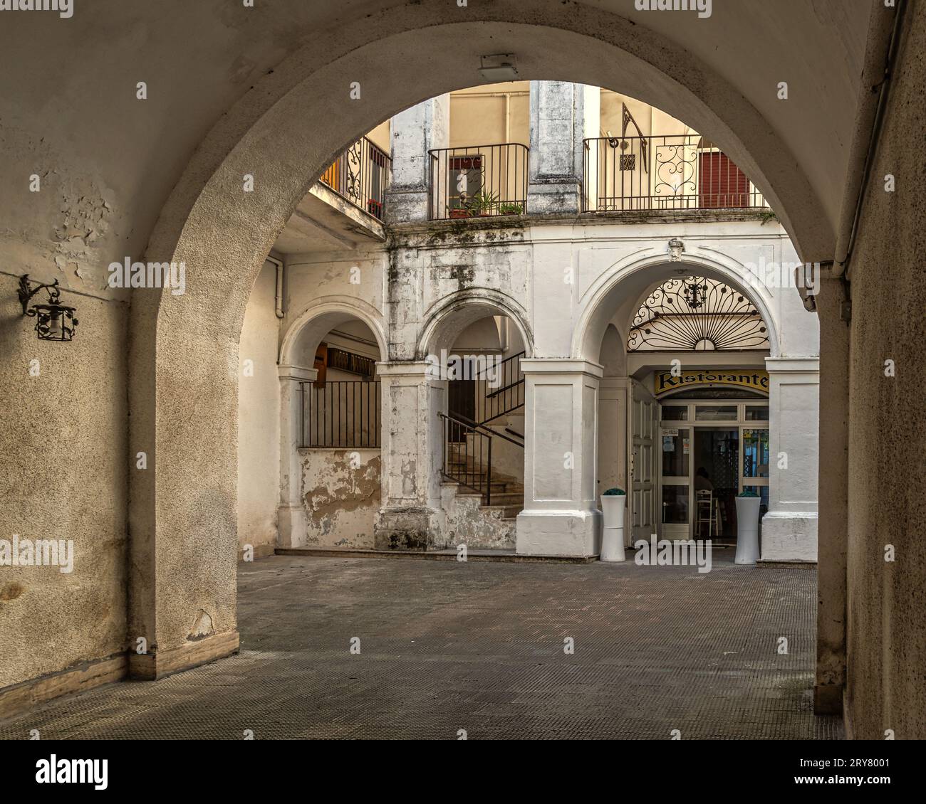 Patio interior de un palacio noble con acceso desde un pasaje cubierto con escalones y pórticos. Monte Sant'Angelo, provincia de Foggia, Italia, Europa Foto de stock