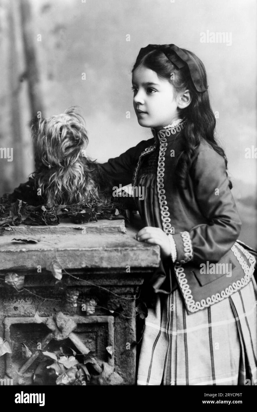 Marian Hubbard 'Daisy' Bell con perro, ca. 1888 Marian Hubbard 'Daisy' Bell, retrato de tres cuartos de longitud, a los ocho años de edad, de pie, mirando hacia la izquierda, con perro, ca. 1888. Foto de stock