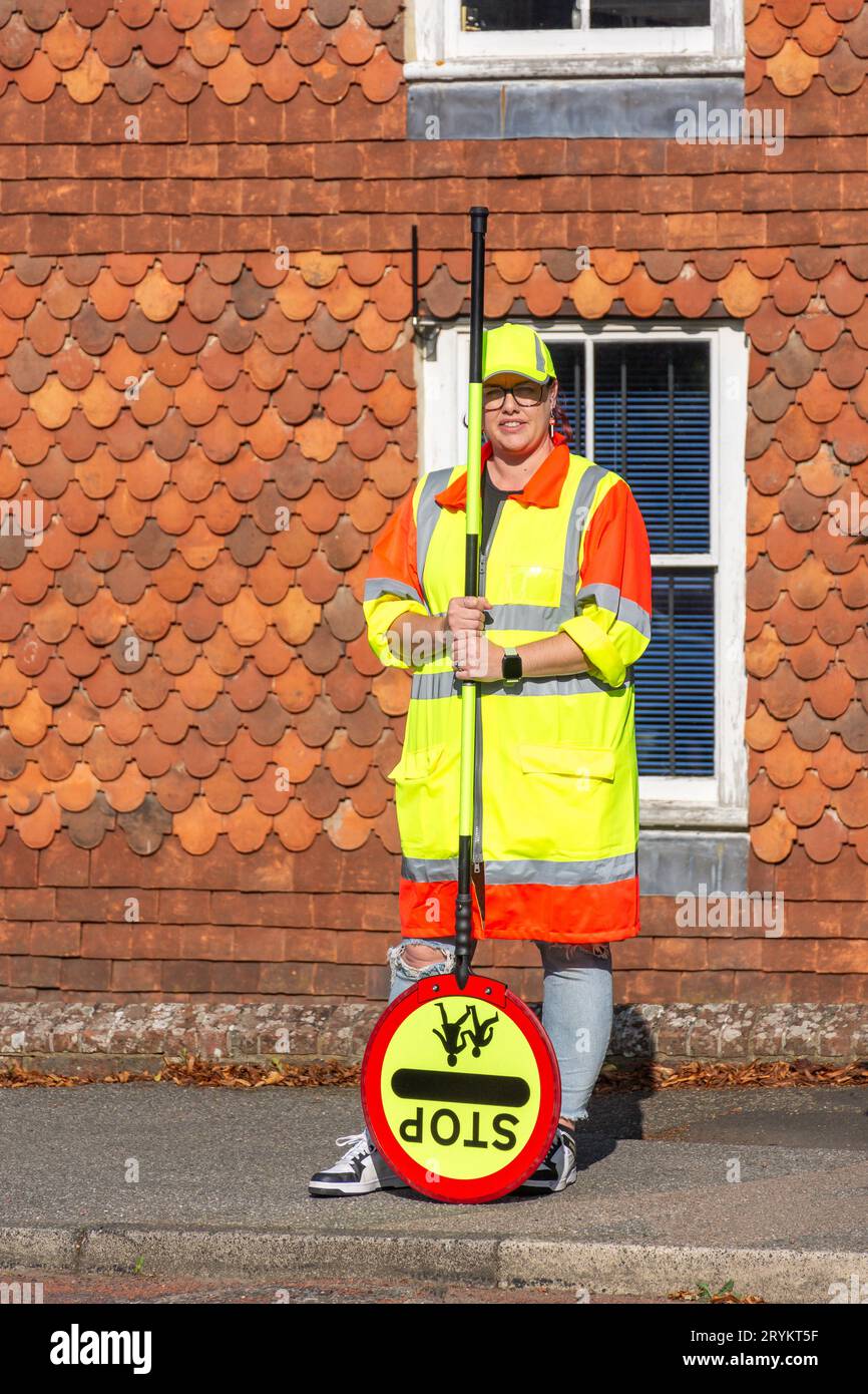 Una 'Lollipop Lady' en el cruce de cebra, High Street, Robertsbridge, East Sussex, Inglaterra, Reino Unido Foto de stock