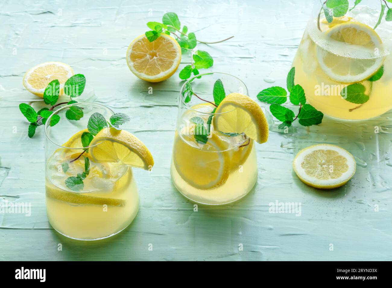 https://c8.alamy.com/compes/2rynd3x/limonada-con-menta-bebida-de-agua-de-limon-con-hielo-dos-vasos-una-jarra-y-limones-sobre-un-fondo-azul-bebida-detox-coctel-casero-fresco-2rynd3x.jpg