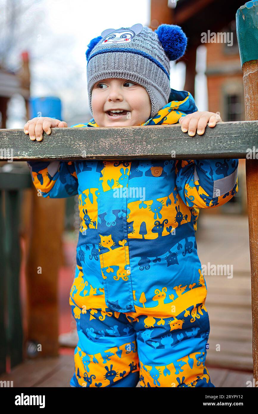 Retrato de un niño lindo jugando en el patio de recreo en invierno Foto de stock