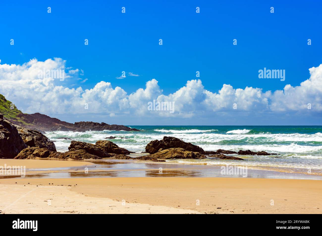 Playa con olas rompiendo contra las rocas Foto de stock