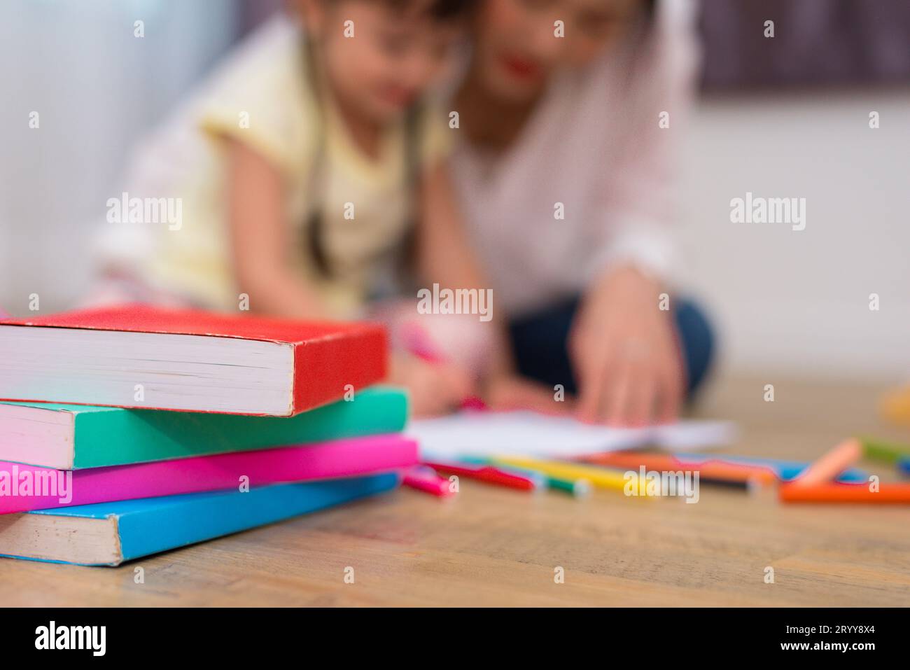 Cierre de libros y color de crayón en el piso con fondo de mamá y niños. Volver a la escuela y el concepto de aprendizaje de la educación artística. Chi Foto de stock