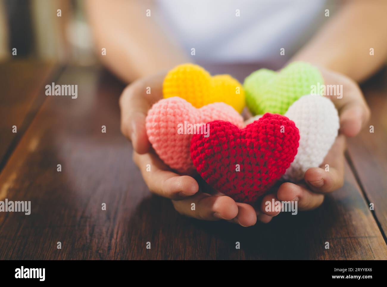 Corazón de hilo de colores mezclados en dar manos. Cerca de colorido hecho a mano. Donación de corazón saludable y concepto de atención médica. Valentin Foto de stock