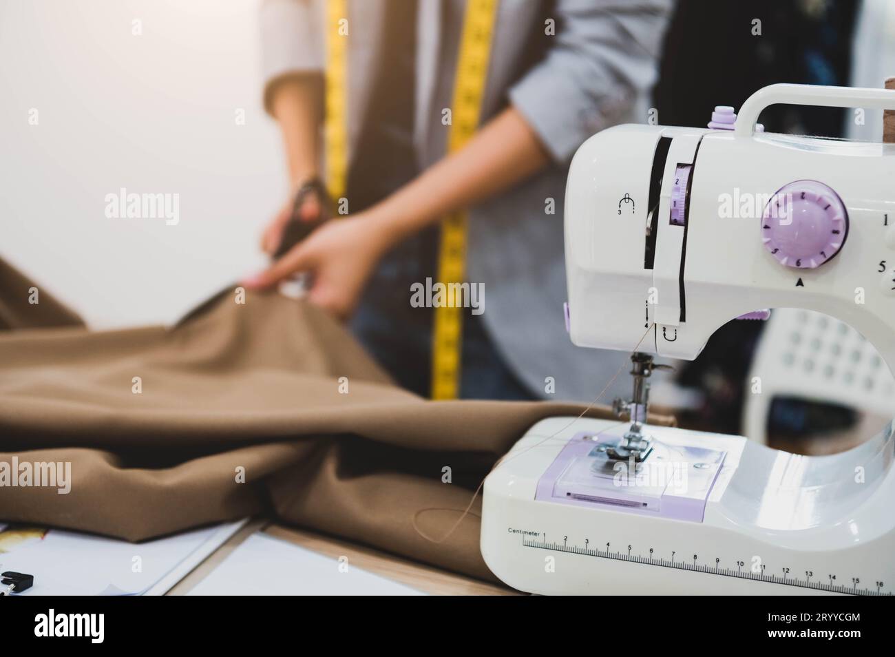 Dressmaker corte vestido de tela en línea de boceto con máquina de coser en primer plano. Diseñador de moda sastre o alcantarilla en taller stud Foto de stock