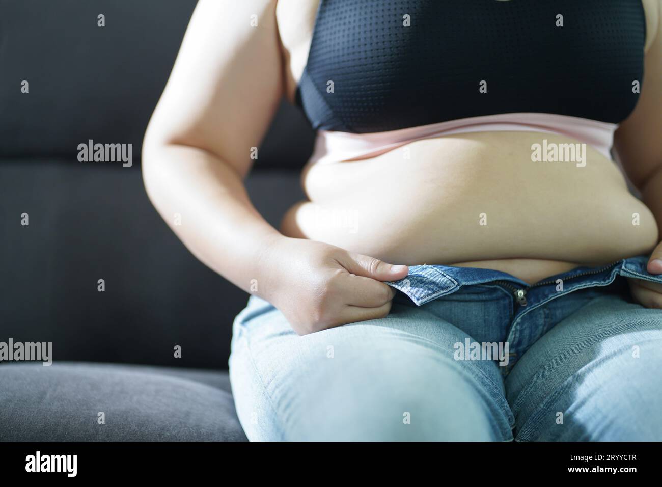 Vientre femenino recortado con sobrepeso y grasa tocando el