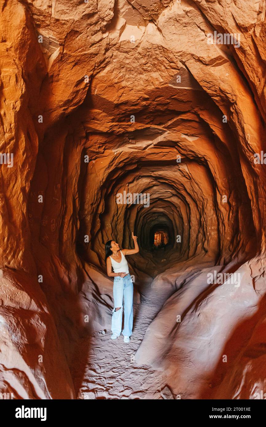 Mujer excursionista joven en el vientre popular del camino de la cueva del túnel del dragón en Kanab Foto de stock