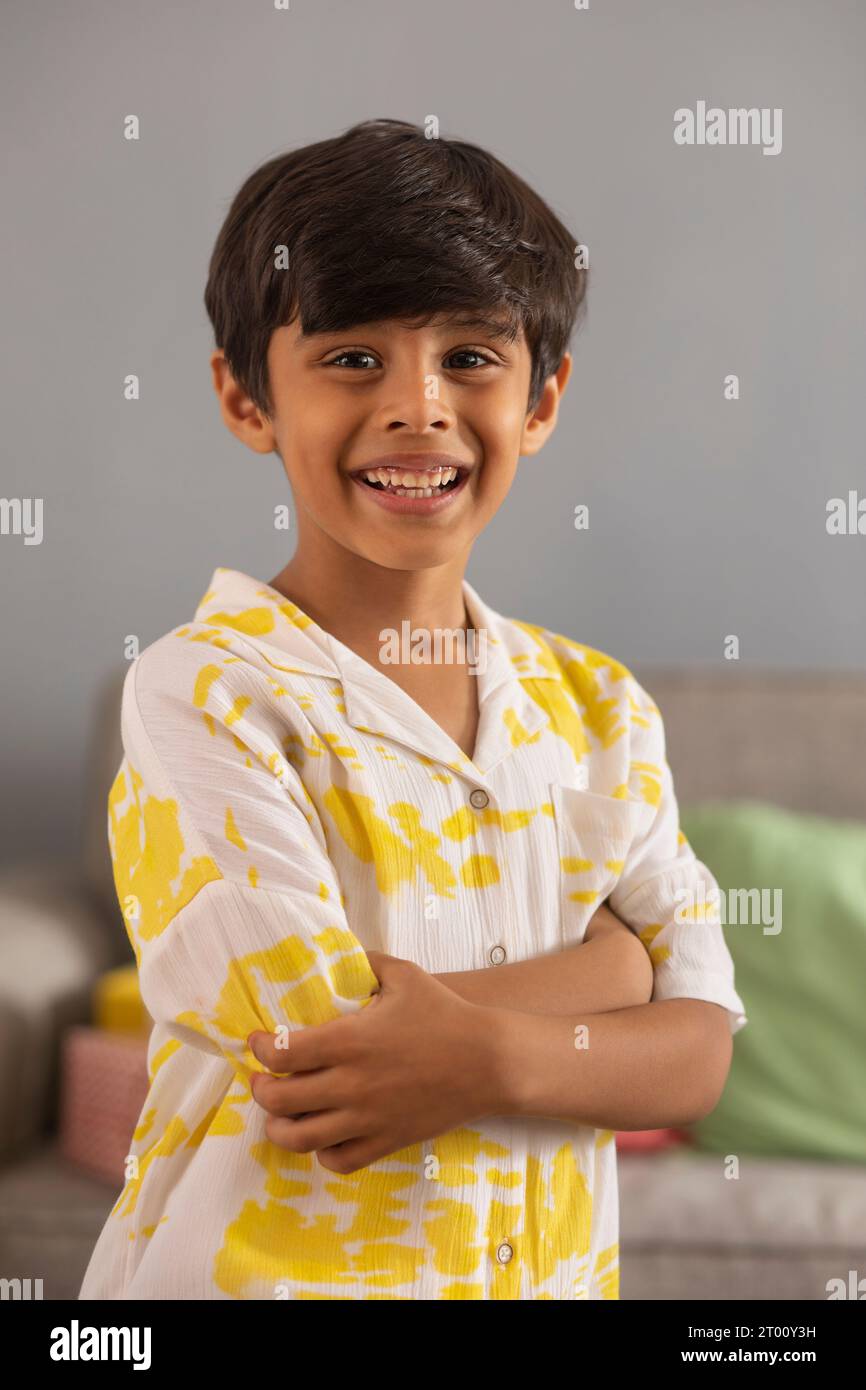 Retrato de un niño alegre de pie con las manos cruzadas Foto de stock