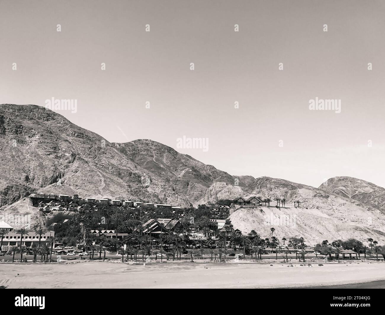 Coche: Orchid Eilat hotel frente a la playa situado en la ladera de la montaña con vistas a la Bahía del Mar Rojo y las Montañas Rojas en blanco y negro Foto de stock