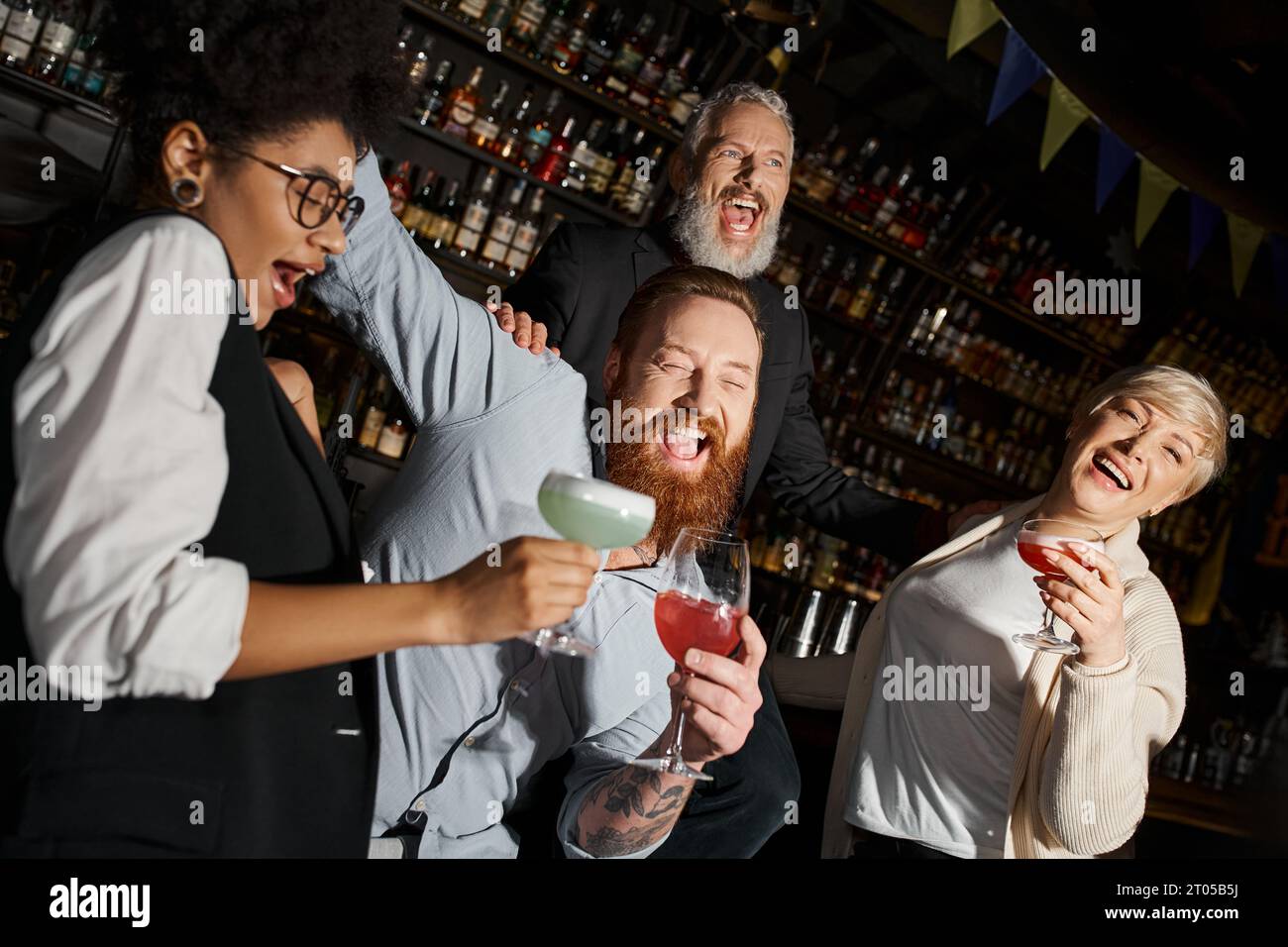 colegas multiétnicos encantados con cócteles riendo en el bar, equipo diverso divirtiéndose después del trabajo Foto de stock