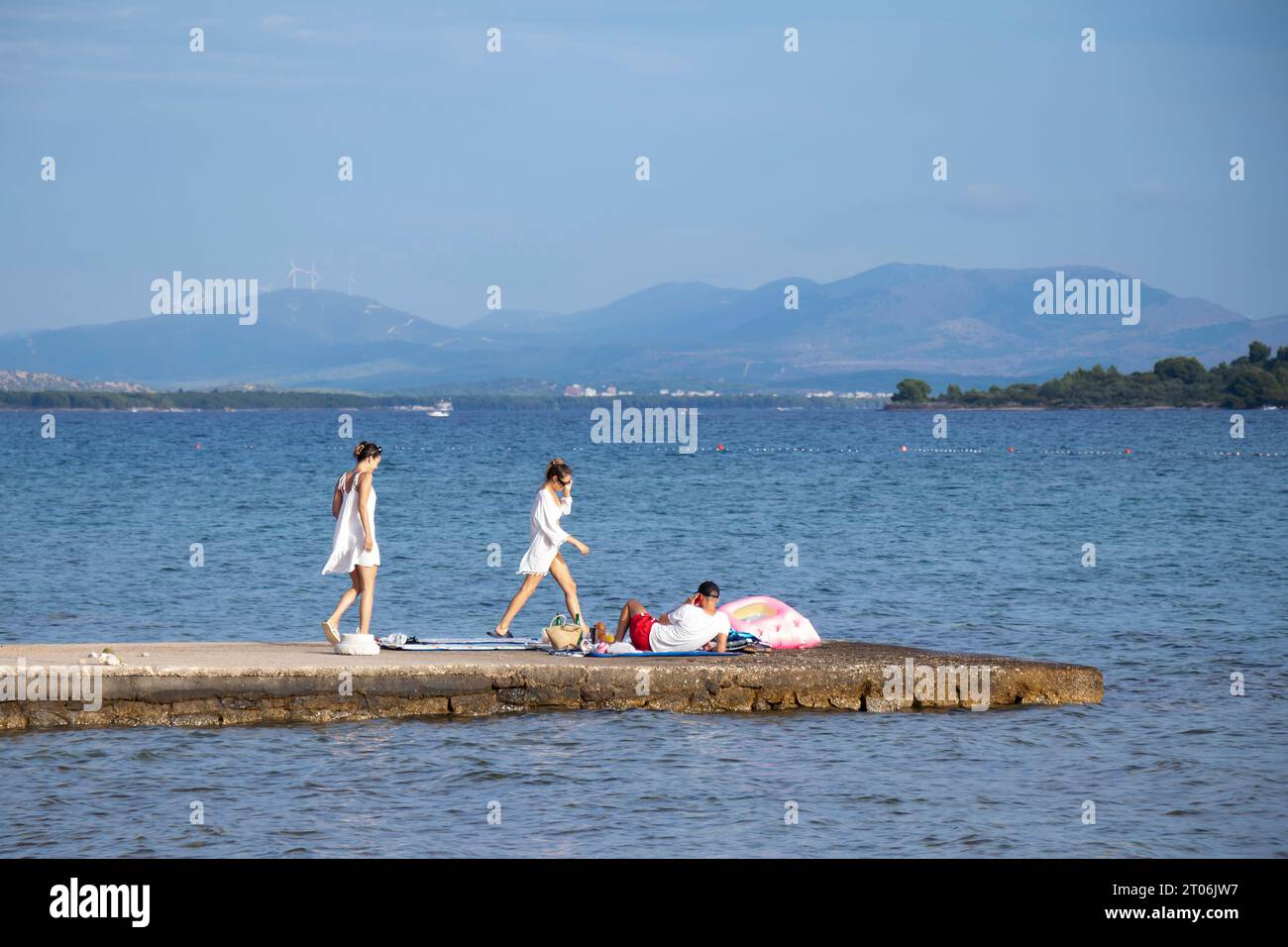 Vodice, Croacia - 16 de septiembre de 2023: Tres jóvenes en el muelle costero Foto de stock
