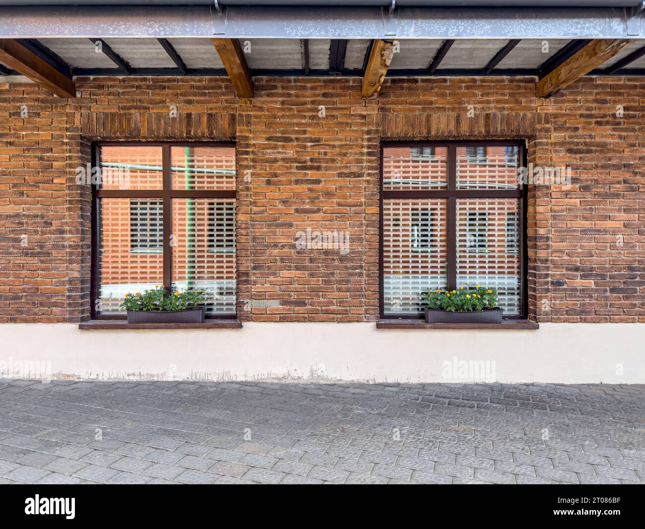 dos ventanas con macetas en la pared de ladrillo rojo. fachada del edificio antiguo renovado. Foto de stock