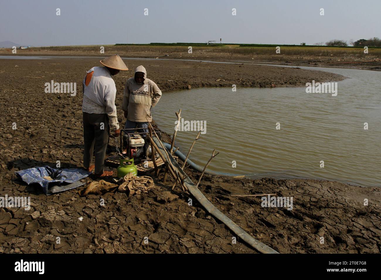 Wonogiri, Java Central, Indonesia. 6º de octubre de 2023. Dos agricultores revisan una manguera para regar los campos de arroz en el embalse de Gajah Mungkur, distrito de Wuryantoro. Se prevé que la estación seca de este año dure más, es decir, hasta finales de 2023 hasta principios de 2024, que es el impacto de El Niño. Actualmente, en medio de la amenaza de la sequía, el volumen de agua cruda del embalse de Gajah Mungkur en la parte superior del río Bengawan Solo en la regencia Wonogiri, Java Central ha disminuido drásticamente. (Imagen de crédito: © Angga Budhiyanto/ZUMA Press Wire) ¡USO EDITORIAL SOLAMENTE! No para Commerci Foto de stock